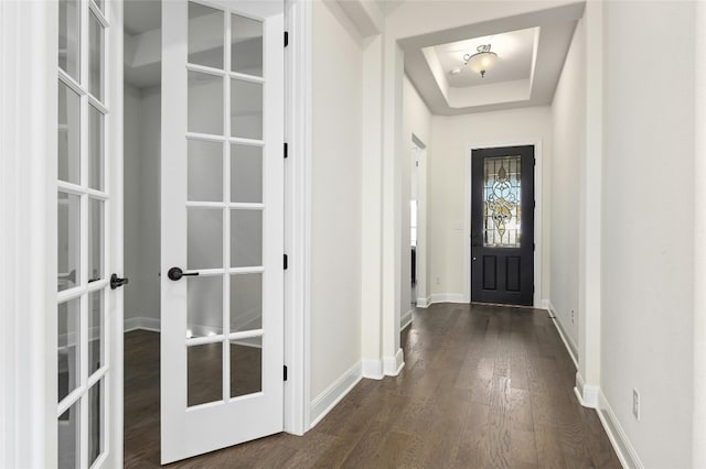 doorway to outside with french doors, a tray ceiling, and dark wood-type flooring