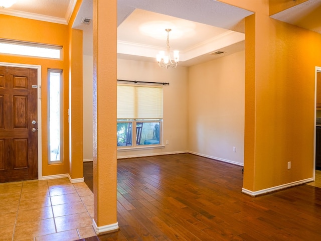 entryway featuring a healthy amount of sunlight, hardwood / wood-style flooring, ornamental molding, and a raised ceiling