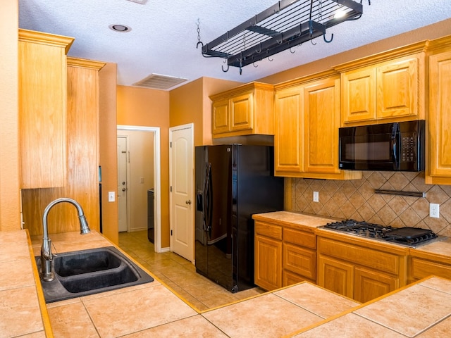 kitchen featuring tile counters, black appliances, and sink