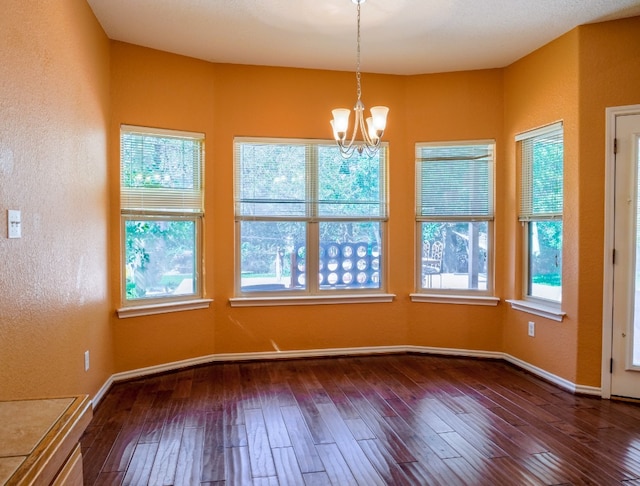 unfurnished dining area featuring an inviting chandelier, dark hardwood / wood-style floors, and a healthy amount of sunlight