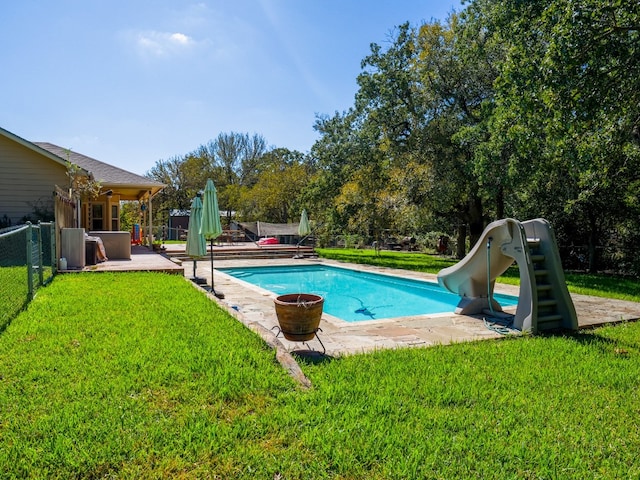 view of swimming pool with a patio, a water slide, and a lawn