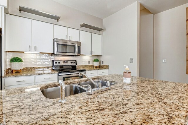 1201 Grove Blvd Unit 2403, Austin, TX 78741 - kitchen with stainless steel appliances, a sink, tasteful backsplash, white cabinetry, and light stone countertops