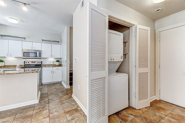 1201 Grove Blvd Unit 2403, Austin, TX 78741 - washroom featuring stacked washing machine and dryer, light stone finish flooring, and baseboards