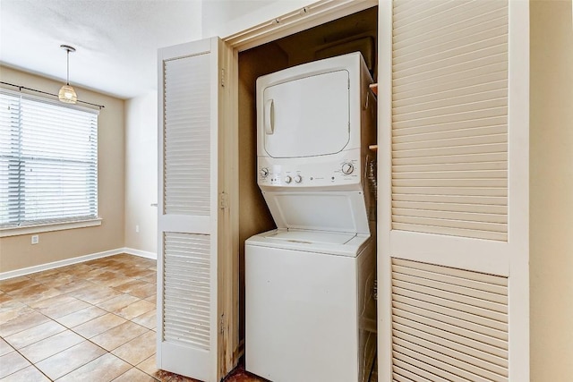 1201 Grove Blvd Unit 2403, Austin, TX 78741 - clothes washing area with baseboards, stacked washing maching and dryer, laundry area, and light tile patterned floors