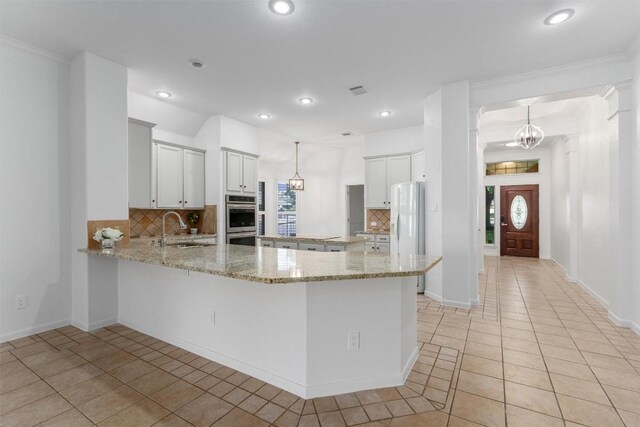 kitchen with white cabinets, backsplash, decorative light fixtures, and sink