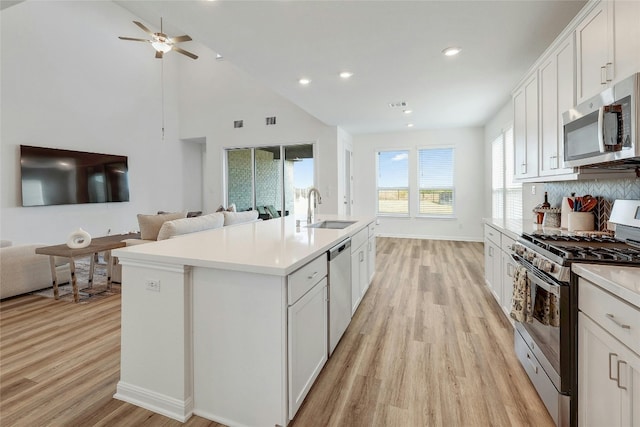 kitchen with appliances with stainless steel finishes, white cabinetry, sink, and a center island with sink