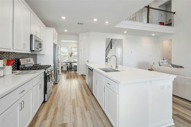 kitchen featuring sink, appliances with stainless steel finishes, white cabinets, and an island with sink