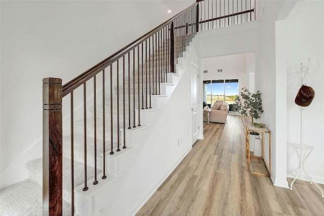 stairs with a high ceiling and hardwood / wood-style flooring