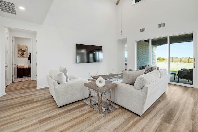 living room with a high ceiling and light hardwood / wood-style flooring