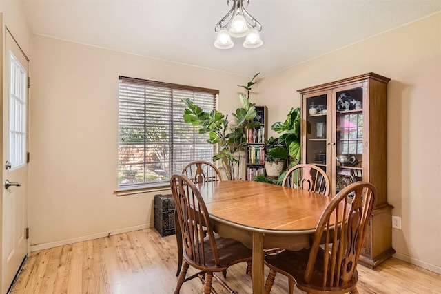 dining space with light hardwood / wood-style floors and a chandelier