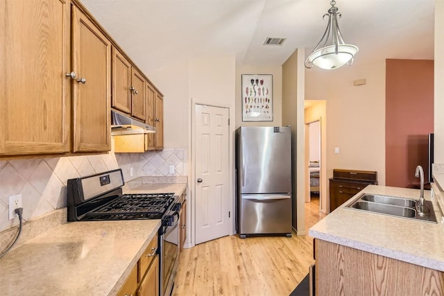 kitchen featuring pendant lighting, sink, light hardwood / wood-style flooring, appliances with stainless steel finishes, and tasteful backsplash