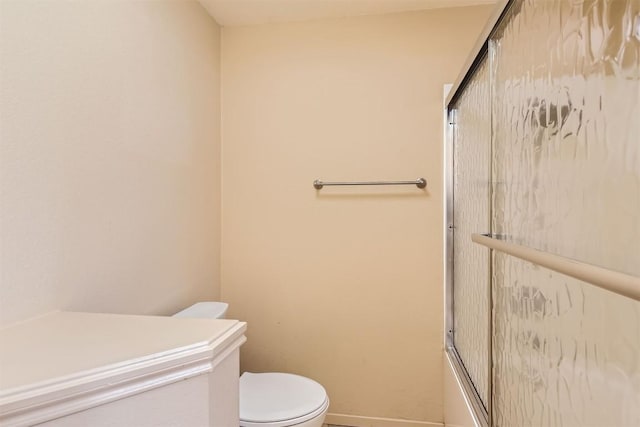 bathroom featuring toilet and bath / shower combo with glass door