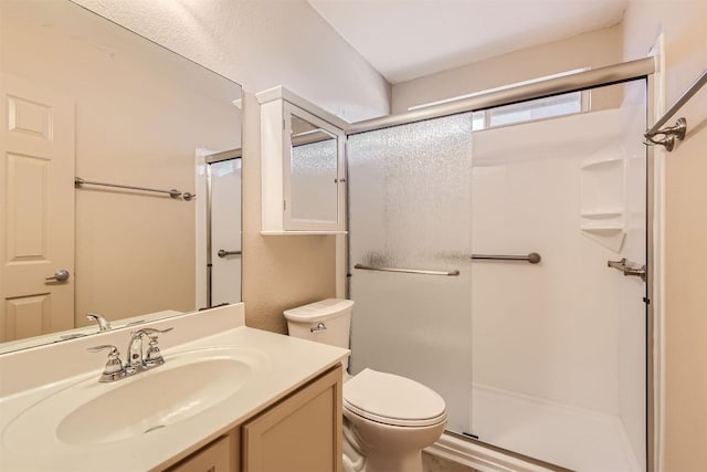 bathroom with a shower with door, vanity, and toilet