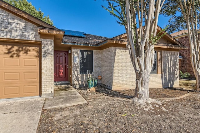 entrance to property featuring solar panels and a garage