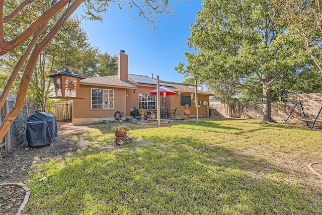 rear view of property featuring solar panels and a yard