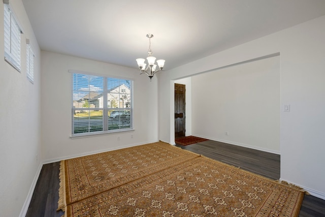 unfurnished room featuring a chandelier and dark hardwood / wood-style floors