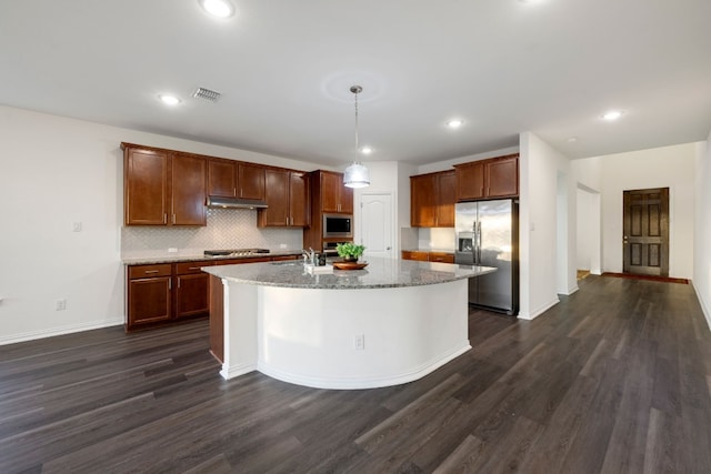 kitchen with stainless steel appliances, pendant lighting, dark wood-type flooring, decorative backsplash, and a kitchen island with sink