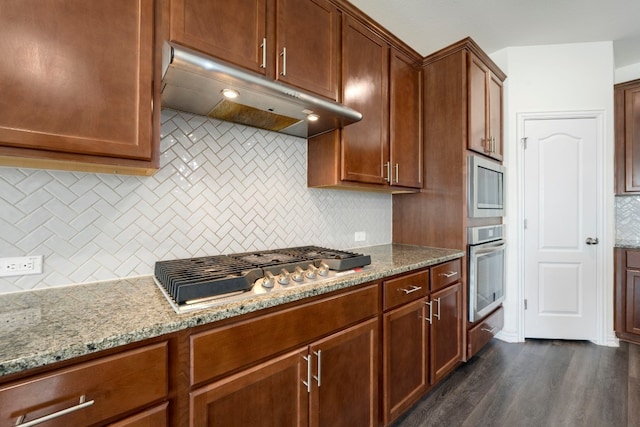 kitchen featuring dark wood-type flooring, light stone counters, stainless steel appliances, and tasteful backsplash