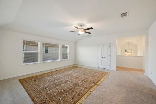 carpeted spare room featuring lofted ceiling and ceiling fan with notable chandelier