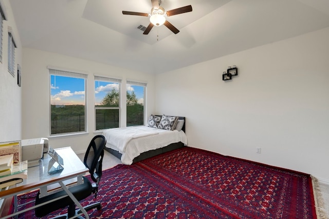 bedroom with carpet floors, a raised ceiling, and ceiling fan