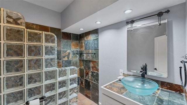 full bath with walk in shower, stone tile flooring, and vanity