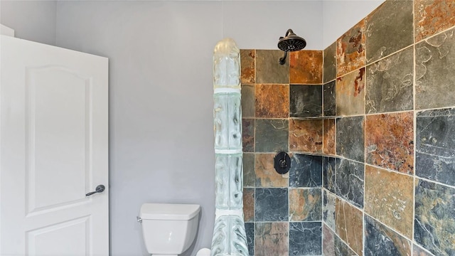 bathroom with a tile shower and toilet