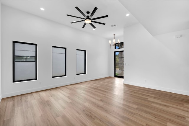 unfurnished living room featuring ceiling fan with notable chandelier and light hardwood / wood-style floors