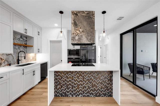 kitchen featuring black appliances, sink, hanging light fixtures, white cabinets, and light hardwood / wood-style flooring