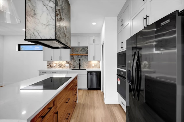 kitchen with white cabinetry, black appliances, pendant lighting, light hardwood / wood-style floors, and sink