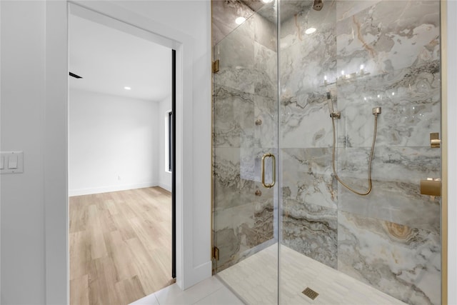 bathroom with hardwood / wood-style floors and a shower with shower door