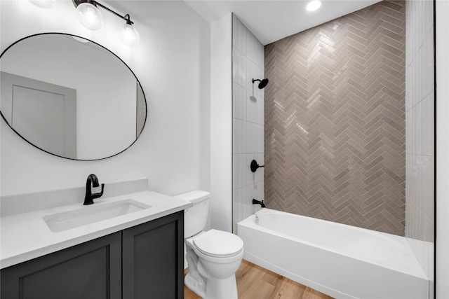 full bathroom with toilet, tiled shower / bath, hardwood / wood-style floors, and vanity