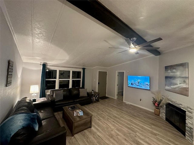 living room with a stone fireplace, hardwood / wood-style flooring, crown molding, lofted ceiling with beams, and ceiling fan