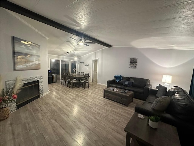 living room featuring a stone fireplace, vaulted ceiling with beams, hardwood / wood-style flooring, and ceiling fan