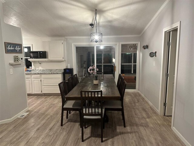 dining space with crown molding and light wood-type flooring