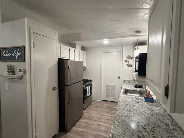 kitchen with sink, light wood-type flooring, hanging light fixtures, stainless steel appliances, and white cabinets