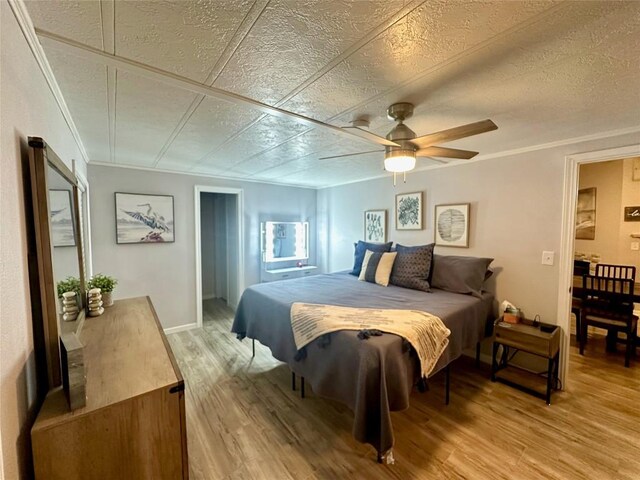 bedroom with crown molding, a textured ceiling, light wood-type flooring, and ceiling fan