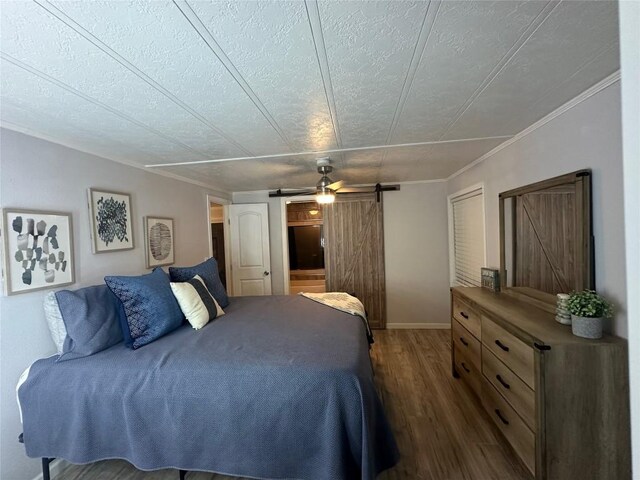 bedroom with ceiling fan, a textured ceiling, a barn door, and dark hardwood / wood-style floors