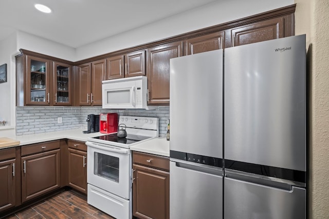 kitchen with decorative backsplash, dark brown cabinets, white appliances, and dark hardwood / wood-style flooring