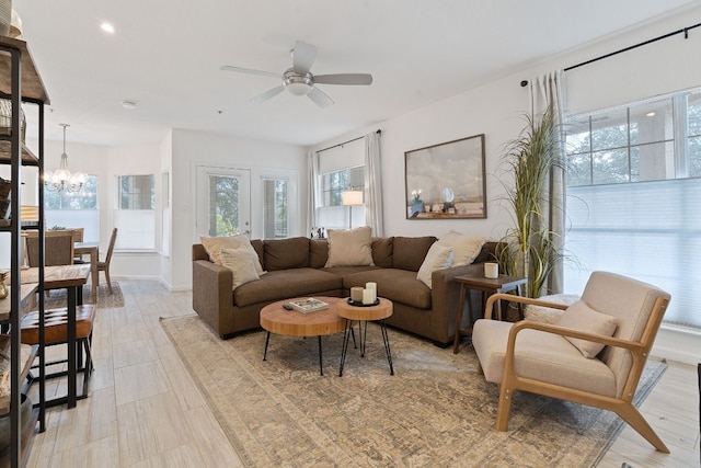 living room featuring a healthy amount of sunlight and ceiling fan with notable chandelier