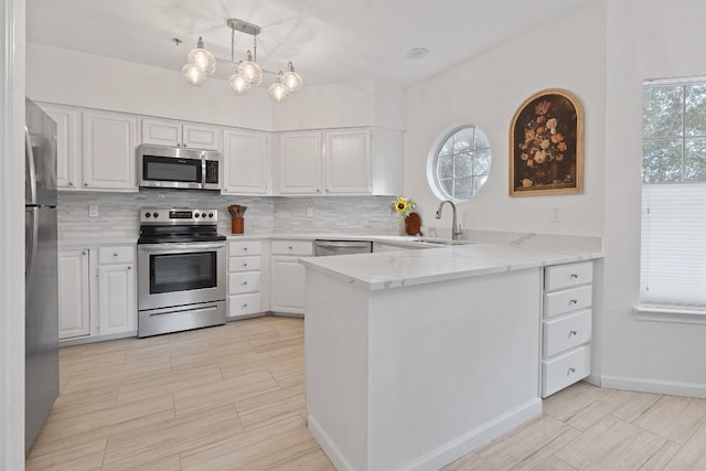 kitchen with pendant lighting, stainless steel appliances, kitchen peninsula, and white cabinets