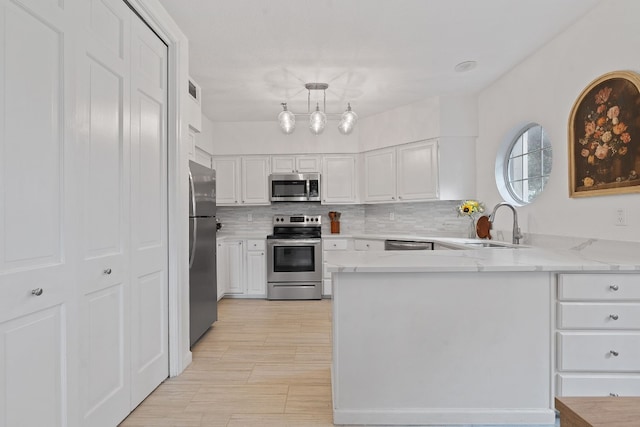 kitchen with sink, white cabinetry, tasteful backsplash, kitchen peninsula, and stainless steel appliances