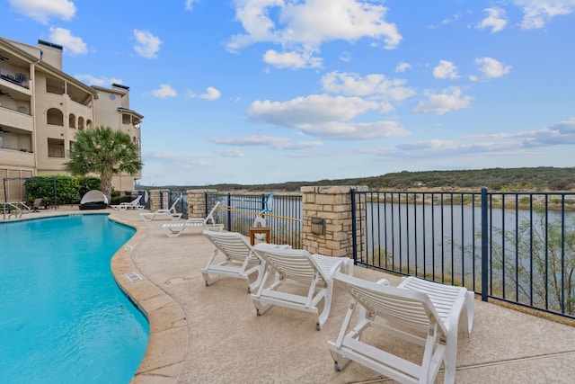 view of swimming pool featuring a water view and a patio area