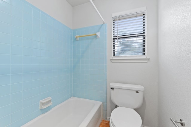 bathroom with tiled shower / bath combo and toilet