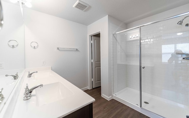 bathroom with vanity, a textured ceiling, wood-type flooring, and a shower with door