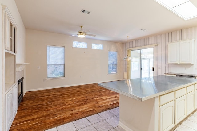 kitchen featuring a center island, pendant lighting, white cabinetry, light hardwood / wood-style floors, and ceiling fan