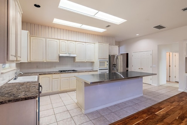 kitchen featuring tasteful backsplash, sink, a kitchen island, stainless steel appliances, and light hardwood / wood-style flooring