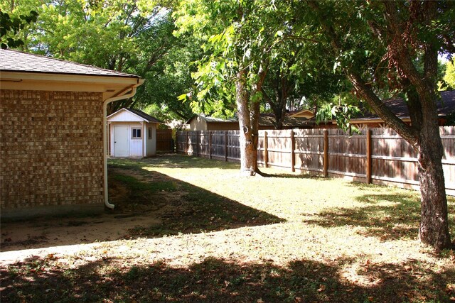 view of yard featuring fence, an outdoor structure, and a shed