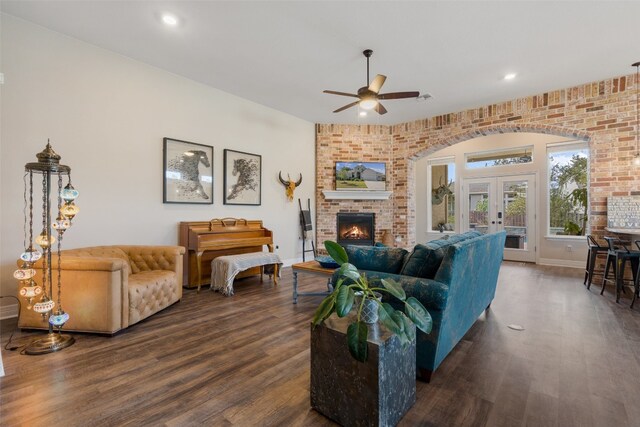 living room with french doors, dark hardwood / wood-style floors, brick wall, a fireplace, and ceiling fan