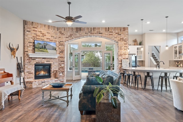 living room with hardwood / wood-style floors, ceiling fan, a brick fireplace, french doors, and sink