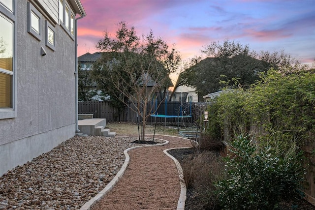 925 Overstreet Ln, Leander, TX 78641 - yard at dusk featuring a trampoline and a fenced backyard